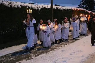 Piger i luciadragter går med lys